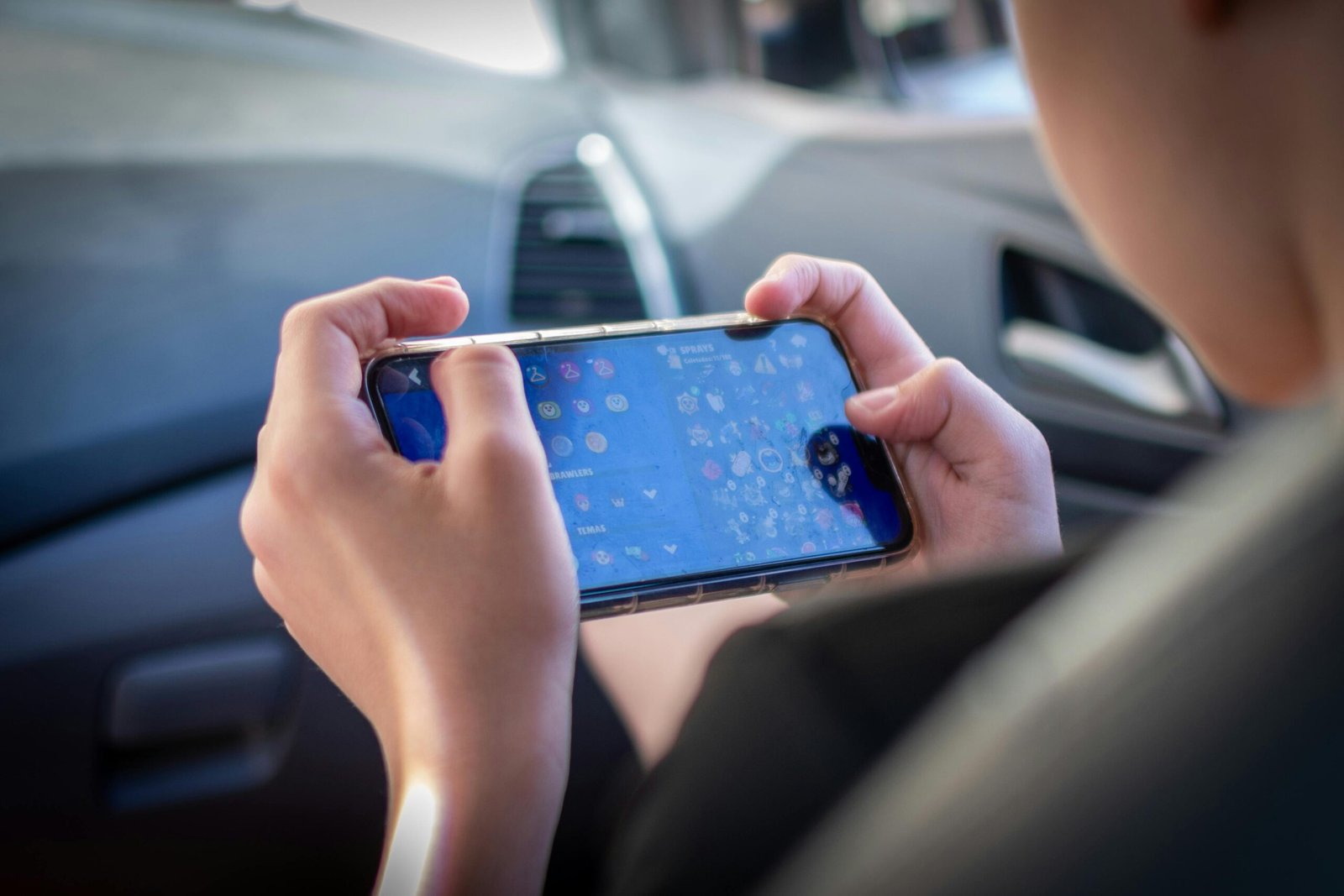 Person playing mobile game on smartphone inside a car